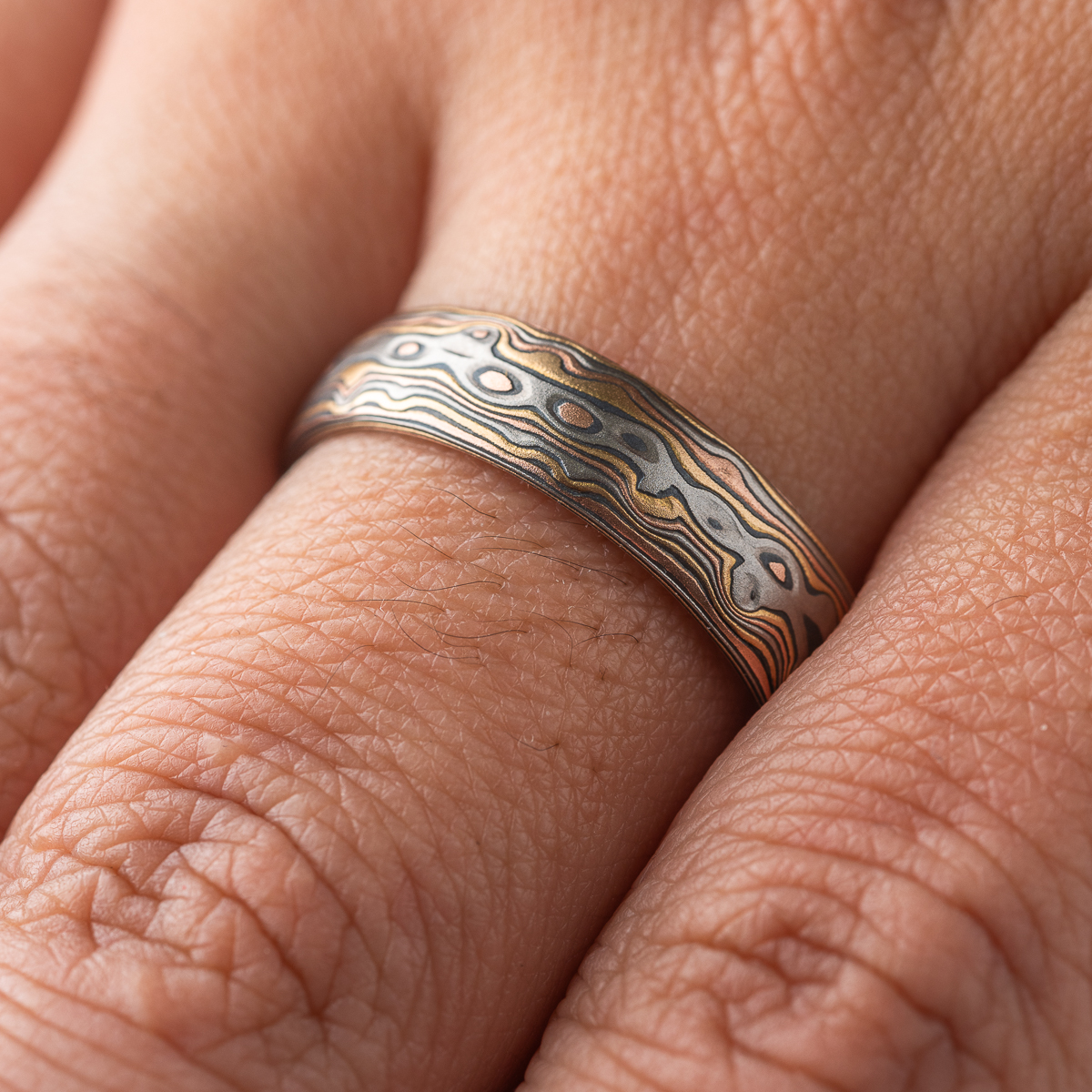 Custom made and patterned mokume gane ring, made with a four metal combination of red gold, yellow gold, palladium and oxidized silver. The pattern is organic, made to resemble woodgrain and natural textures.