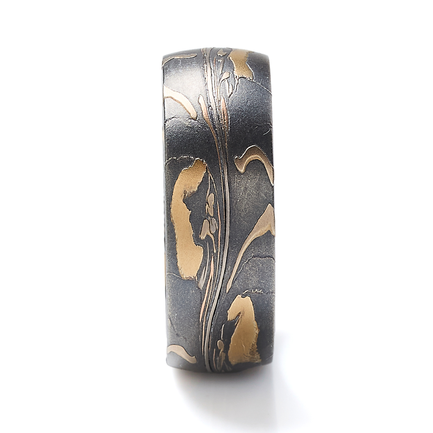Arn Krebs mokume gane mens ring made in an organic unique pattern, with layers of yellow gold, red gold, palladium, and silver that's been oxidized. The pattern resembles pressed flower petals on a dark backdrop.