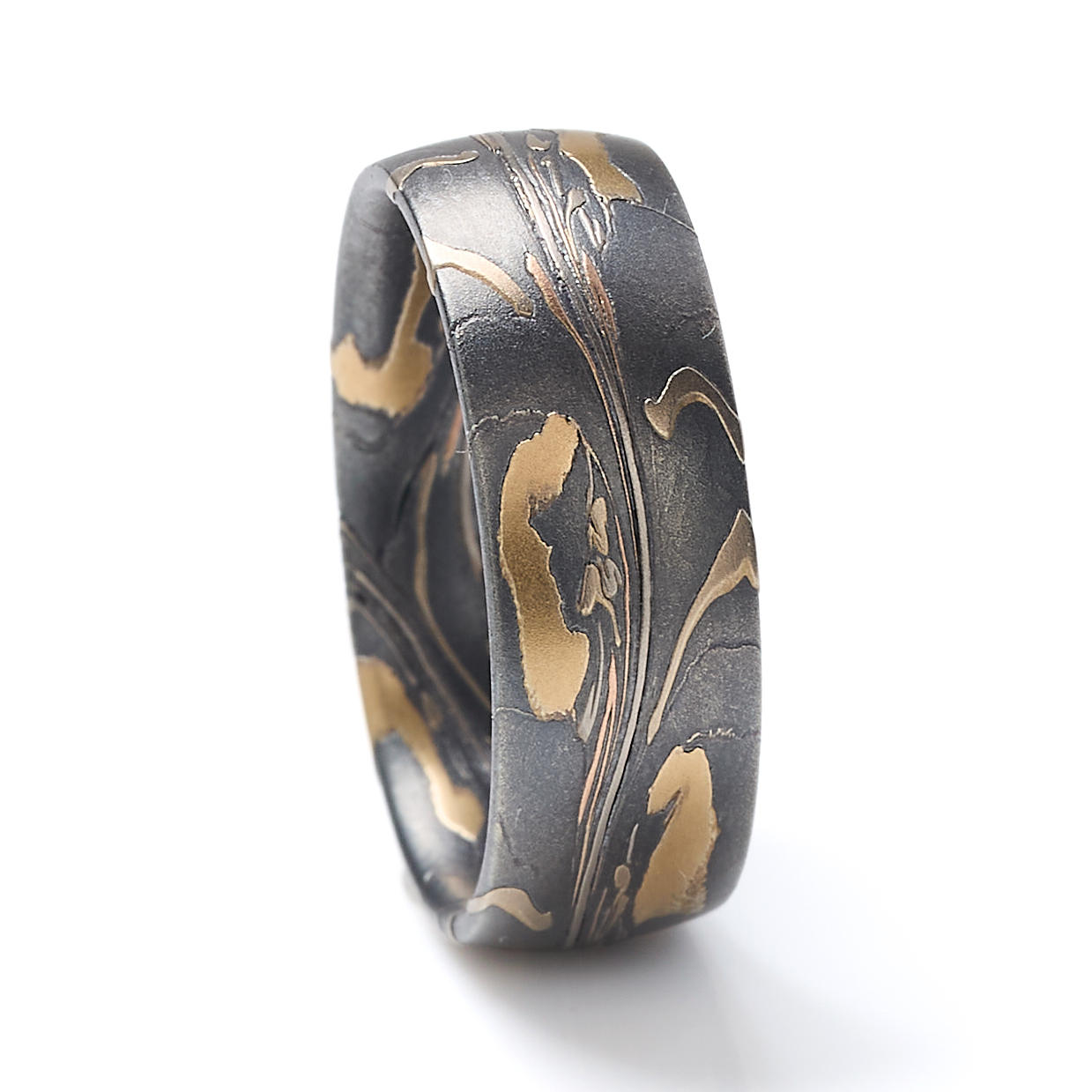 Arn Krebs mokume gane mens ring made in an organic unique pattern, with layers of yellow gold, red gold, palladium, and silver that's been oxidized. The pattern resembles pressed flower petals on a dark backdrop.