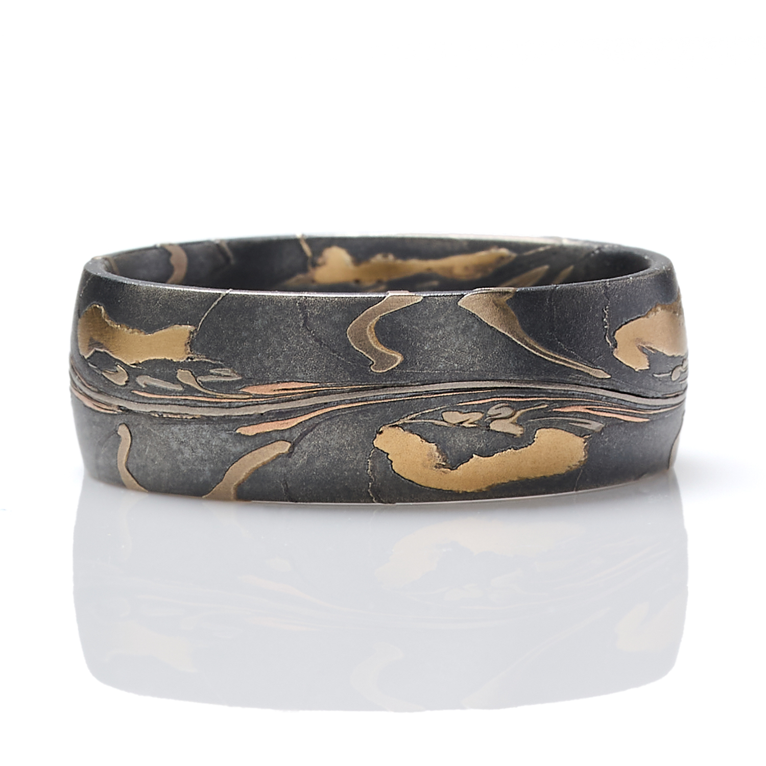 Arn Krebs mokume gane mens ring made in an organic unique pattern, with layers of yellow gold, red gold, palladium, and silver that's been oxidized. The pattern resembles pressed flower petals on a dark backdrop.