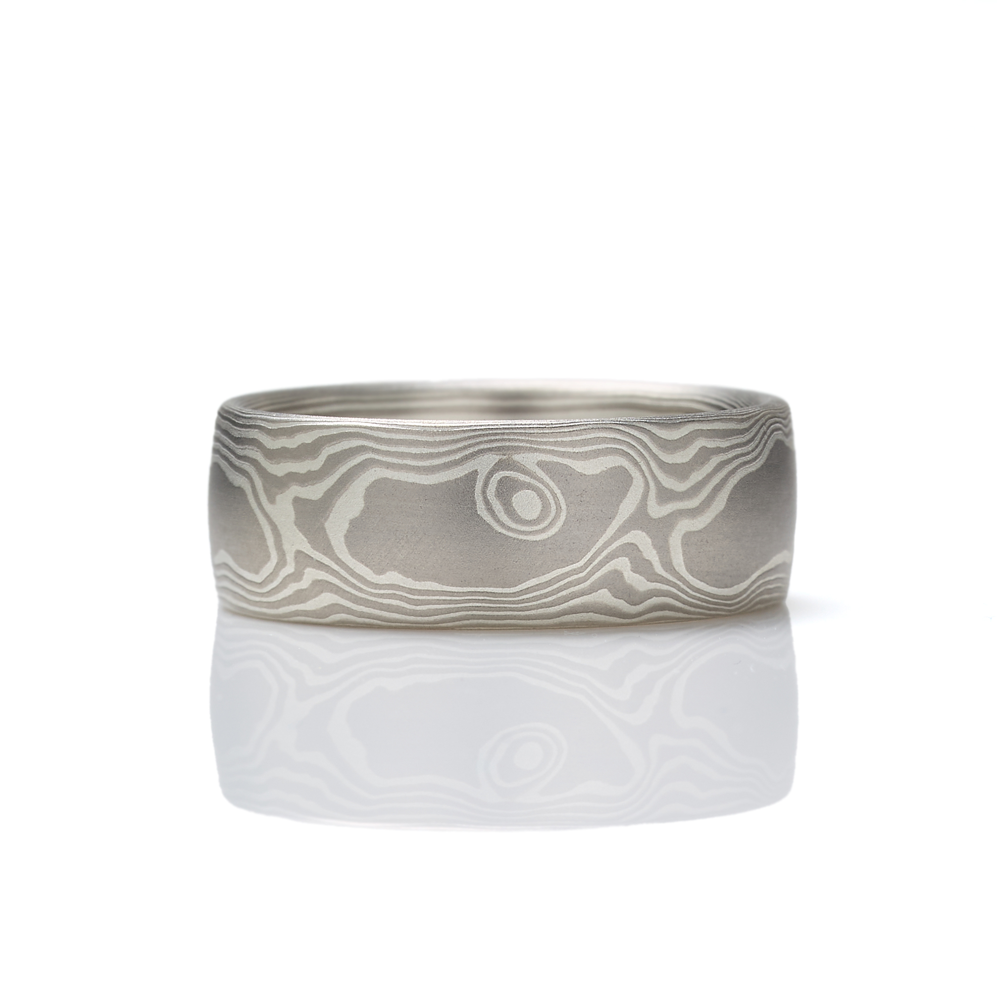 Mokume gane ring patterned in a classic woodgrain style, made with layers of palladium and silver, lightly etched for a slight texture, wide to suit a men's style, and with a low dome profile.